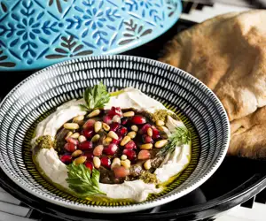 dish garnished with pine nuts and pomegranate